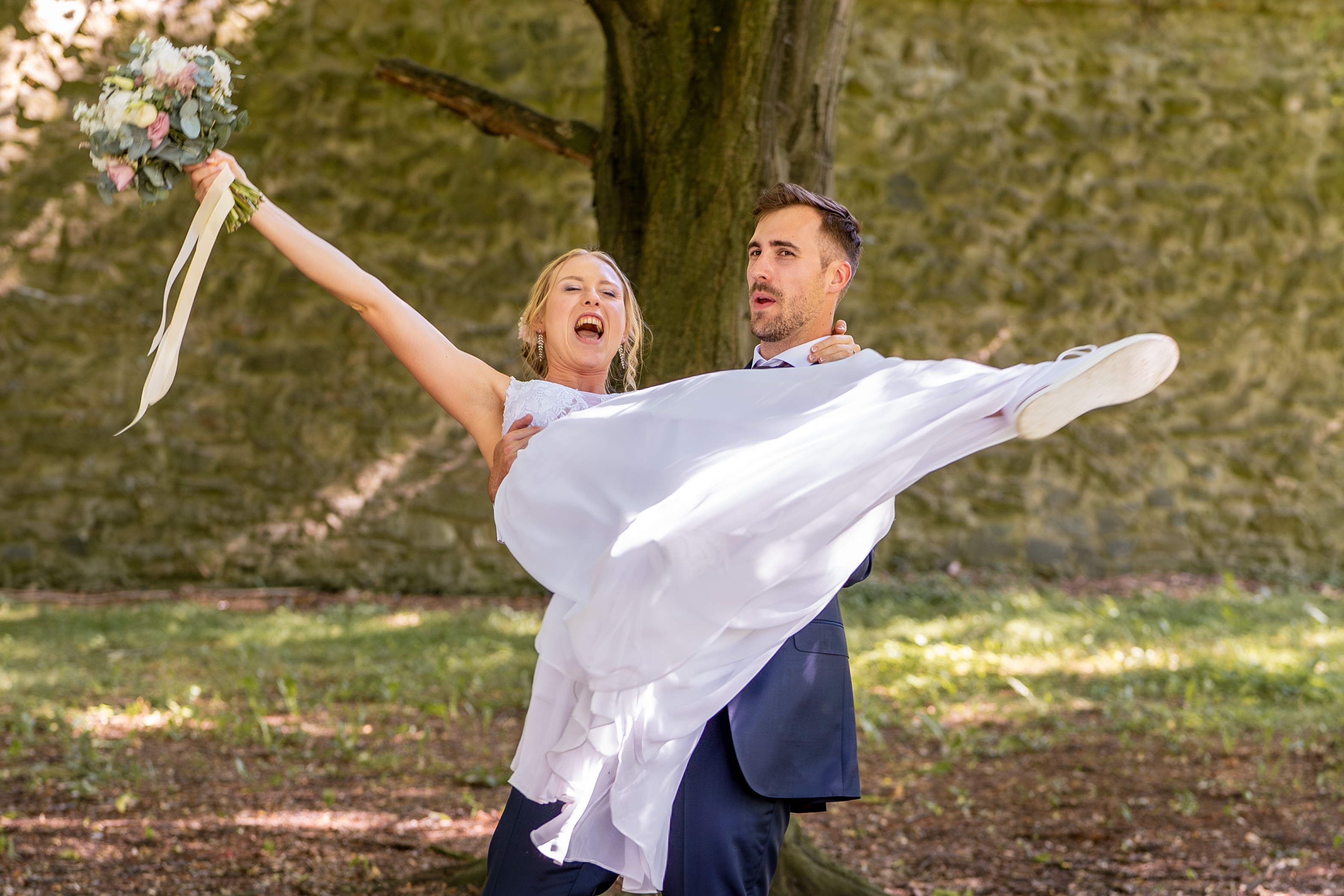 Groom lifting laughing bride outdoor wedding Prague